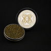 An open round metal tin of black sturgeon caviar with visible dark gold roe, shown next to its lid. The lid features a white circular label.