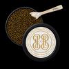 Open round black tin of PRL Caviar sturgeon caviar with golden-brown caviar beads visible, a small spoon marked PRL, and the branded lid placed on top against a black background.
